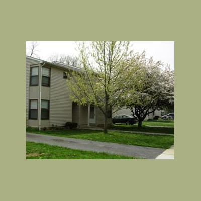 Two story building with beige siding, multiple windows, and a front door.