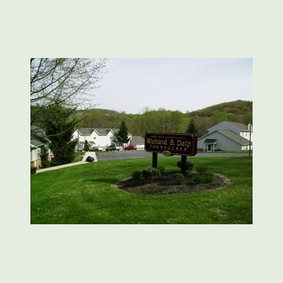 Richard B. Delp Townhouses sign, situated on a grassy area with buildings and trees surrounding it.
