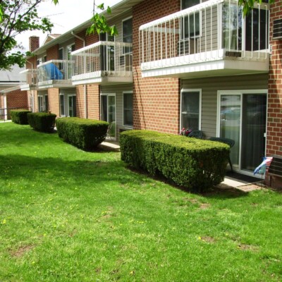 Two-story apartment building with a green lawn and bushes.