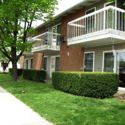 Two-story apartment building with a green lawn and bushes.